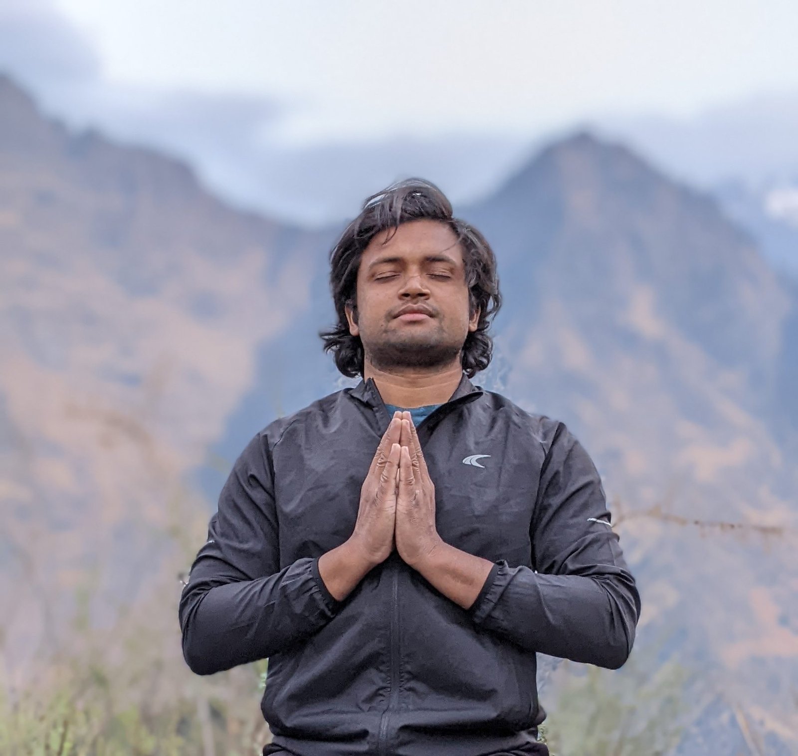 Yogi Gajendra in seated meditation outdoors, hands folded in namaste