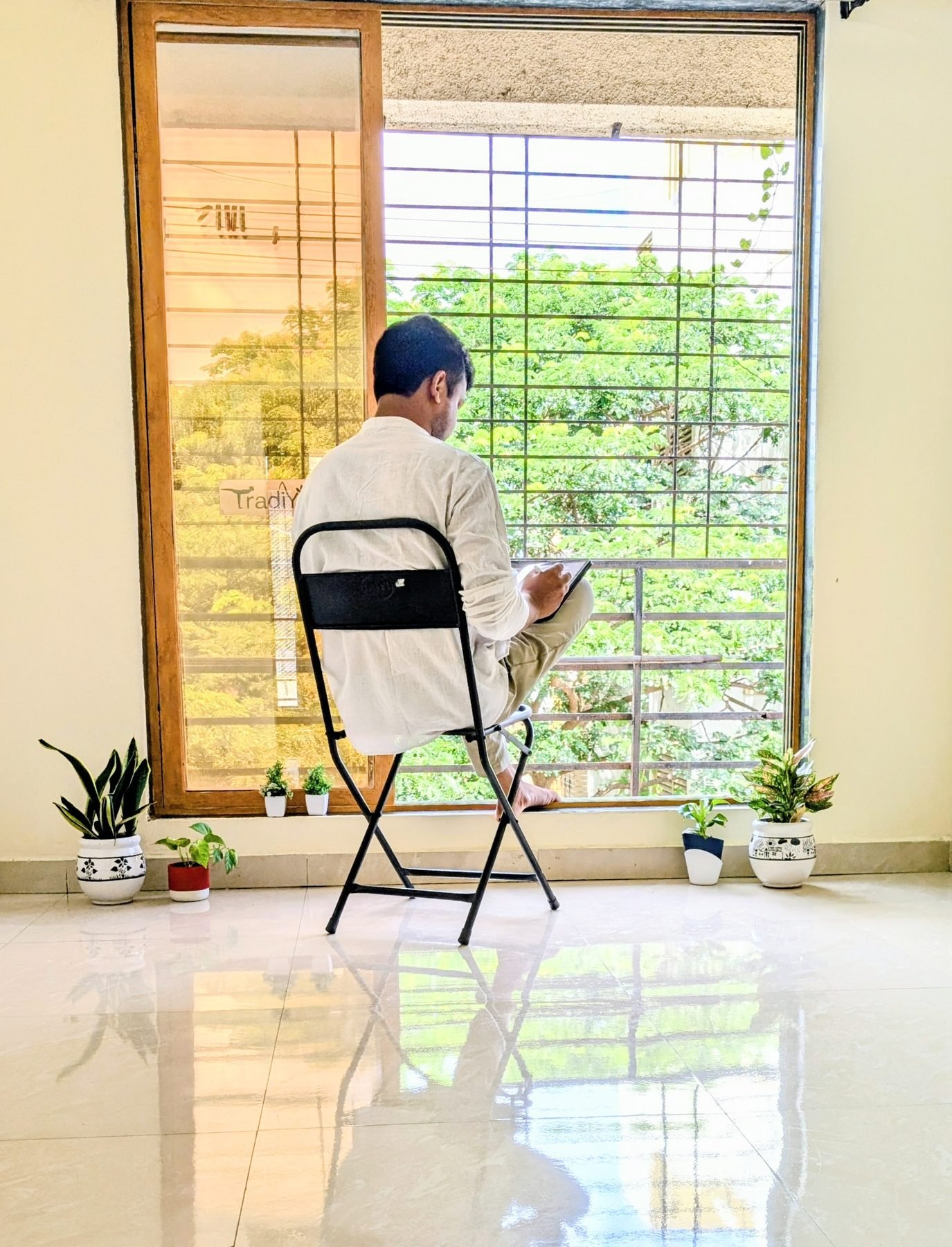 Yogi Gajendra seated with a tablet by a window, preparing for a live online session