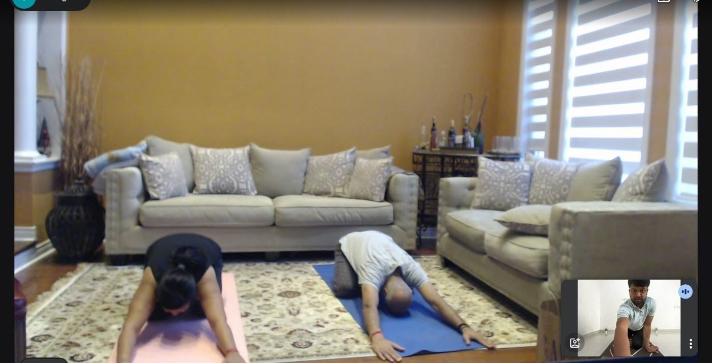 Two students practising a grounded forward-fold together during a home session